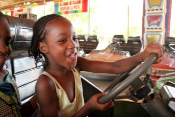 Little girl on bumper car in African amusement park