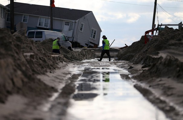 City workers turn off a water main on a street filled with sand in Long Beach Island, N.J.