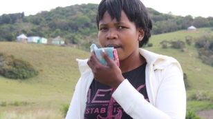 South African woman holds a cloth in front of her mouth as she coughs up blood. (VOA/D.Taylor)