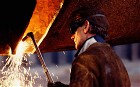 Close-up side view of a man working in ship building yard welding with oxyacetylene torch