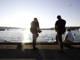 Security team members talk with locals on a pier.
