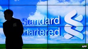 Silhouette of man in front of Standard Chartered bank logo
