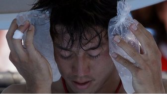 Kei Nishikori of Japan holds an ice pack to his face 
