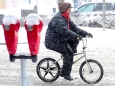 A man rides a bicycle through the snow
