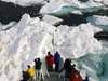Photo of tourists on boat&#x27;s bow in pack ice