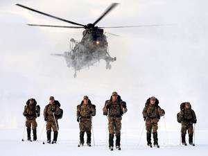 21 February 2014: (L to R) Corporal Tom Rounding 30 Cdo, Corporal Anthony Fairclough CLR, Marine Tom Barker 45 Cdo; Colour Sergeant Richard Hayden 40 Cdo; Captain Samuel Moreton RM 42 Cdo and Lance Corporal Matt Robb 45 Cdo being over flown by a Royal Navy Sea King Mk4 helicopter from 845 Naval Air Squadron as they ski across a frozen lake near Bardufoss northern Norway as part of the Royal Marines 1664 challenge