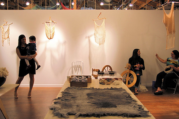Knitted pieces by Amabelle Aguiluz are installed near baskets of raw fleece shearings and a felted rug at the Fibershed Los Angeles pop-up.