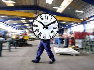 28 March 2014: An employee of the Bodet Company carries a clock at the plant of Trementines, France
