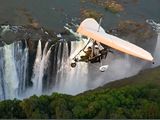 Photo: Microlight plane flying over waterfall