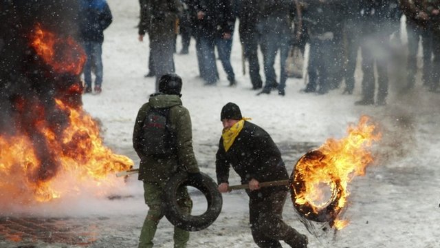 A man carries a burning tyre during clashes between police and protesters in Kiev 