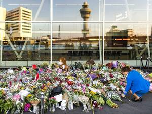 The tower and airport buildings are reflected in the window of a terminal building as an airline hostess arranges floral tributes placed at the the Schiphol Airport, near Amsterdam, The Netherlands