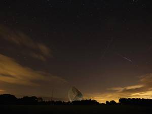 A Perseid meteor (right) streaks across the sky past the light trail of an aircraft over the Lovell Radio Telescope at Jodrell Bank in Holmes Chapel, United Kingdom