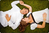 couple lying in grass holding hands