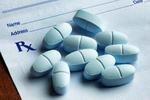 Blue hydrocodone acetaminophen tablets lying on a blue prescription form.