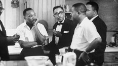 Reverend Dr. Martin Luther King, Jr. (left) and Ralph Abernathy (right) talking with Freedom Riders at the home of Dr. Richard Harris in Montgomery, AL.