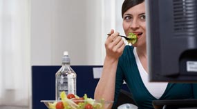Woman eating a salad at work desk
