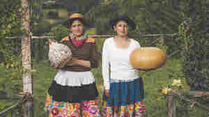 Standing in their backyard in Cochas Grande, Peru, Katya and Blanca Cantos, hold the fruit of their labor. The gourd at left shows scenes from a potato harvest. The just-started gourd at right will tell the story of an ancestor's epic trek.