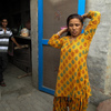 Saroj's teenage son watches her comb her hair before she heads to work.