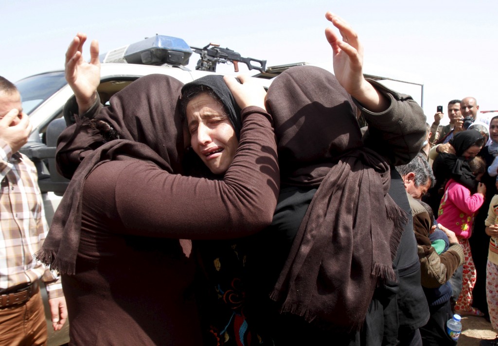 Members of the minority Yazidi sect hug each other on the outskirts of Kirkuk
