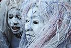 A troupe of dancers wears white face and raffia hair for a cultural festival in Inhambane, Mozambique.