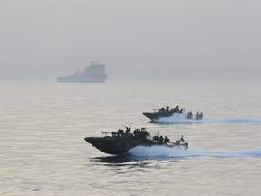 USS Riverine gun-boats patrol as British Royal Navy Ship Cardigan Bay is seen behind at the Middle East Gulf