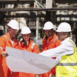 Workers with blueprints at oil refinery