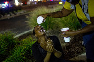 A protestor had her eyes washed out after being tear-gassed by police along West Florissant Road in Ferguson, Mo.