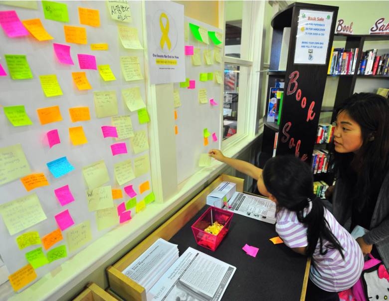 Hannah Cha and her daughter Kayla, 5, post a note to a bulletin board dedicated to the South Korea ferry disaster victims at the Palisades Park library on Friday.