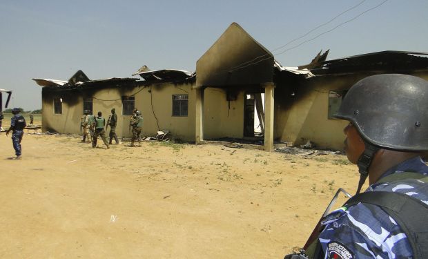 In this photo taken on Monday, Oct. 28, 2013, police and soldiers stand in front of a  burnt out army barracks  following an attack by Boko Haram in in Damaturu, Nigeria. Nigerian. (AP Photo)