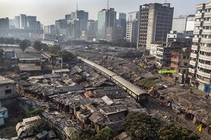 A view across the track-side slums in central Dhaka, with the buildings of the Karwan Bazaar district rising up in the background, 18 March