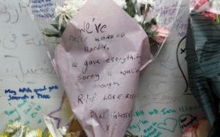 Floral tributes, one bearing a message from the London Fire Brigade are placed near The Grenfell Tower block,