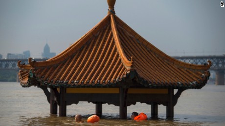 People swim past the top of a pagoda at a flooded riverside park in Wuhan in central China&#39;s Hubei Province on Monday, July 3, 2017. Dozens have been killed and more are missing as heavy rains pummeled southern China, flooding towns, cutting off power and halting traffic, China&#39;s Ministry of Civil Affairs said Tuesday. (Chinatopix Via AP)