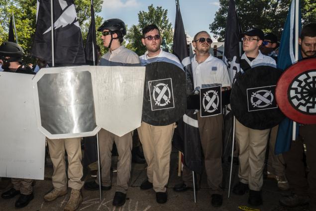 James Fields Jr. (c.) of Maumee, Ohio, holds a shield associated with the hate group Vanguard America as he and others stand in front of the statue of Robert E. Lee at Lee Park in Charlottesville, Va. around 11 a.m. Saturday morning.