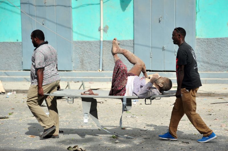 Residents carry an injured man wounded during a complex car bomb attack targeting a Mogadishu hotel on January 25, 2017