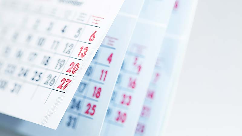 Months and dates shown on a calendar whilst turning the pages with shallow depth of field