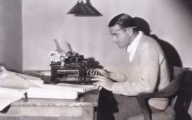 Black & white image of man working at typewriter