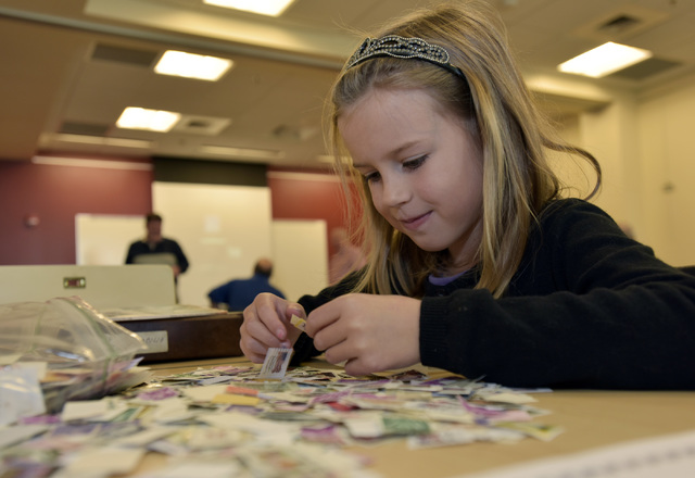 Jesse White, 7, of Plymouth, searches through a collection of postage stamps during the Wyoming Valley Stamp Club’s meeting Saturday at the Hoyt Library in Kingston. 