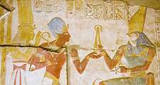 Ancient Egyptian carving of Pharaoh Seti I holding his flail before the god of the underworld Osiris with Horus behind him. Abydos Temple, Egypt. Ancient carving, on public display for 2,000 years