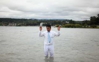 A member of an Evangelical church prays in the Villarrica lake before baptizing the followers at a ceremony in Villarrica town, Chile March 11, 2018.
