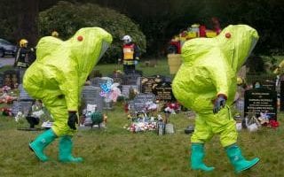 Fire officers in hazard suits place a tent over the grave of poisoned spy Sergey Skripal's son