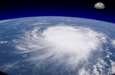 view from space of a giant hurricane over the ocean with moon in background