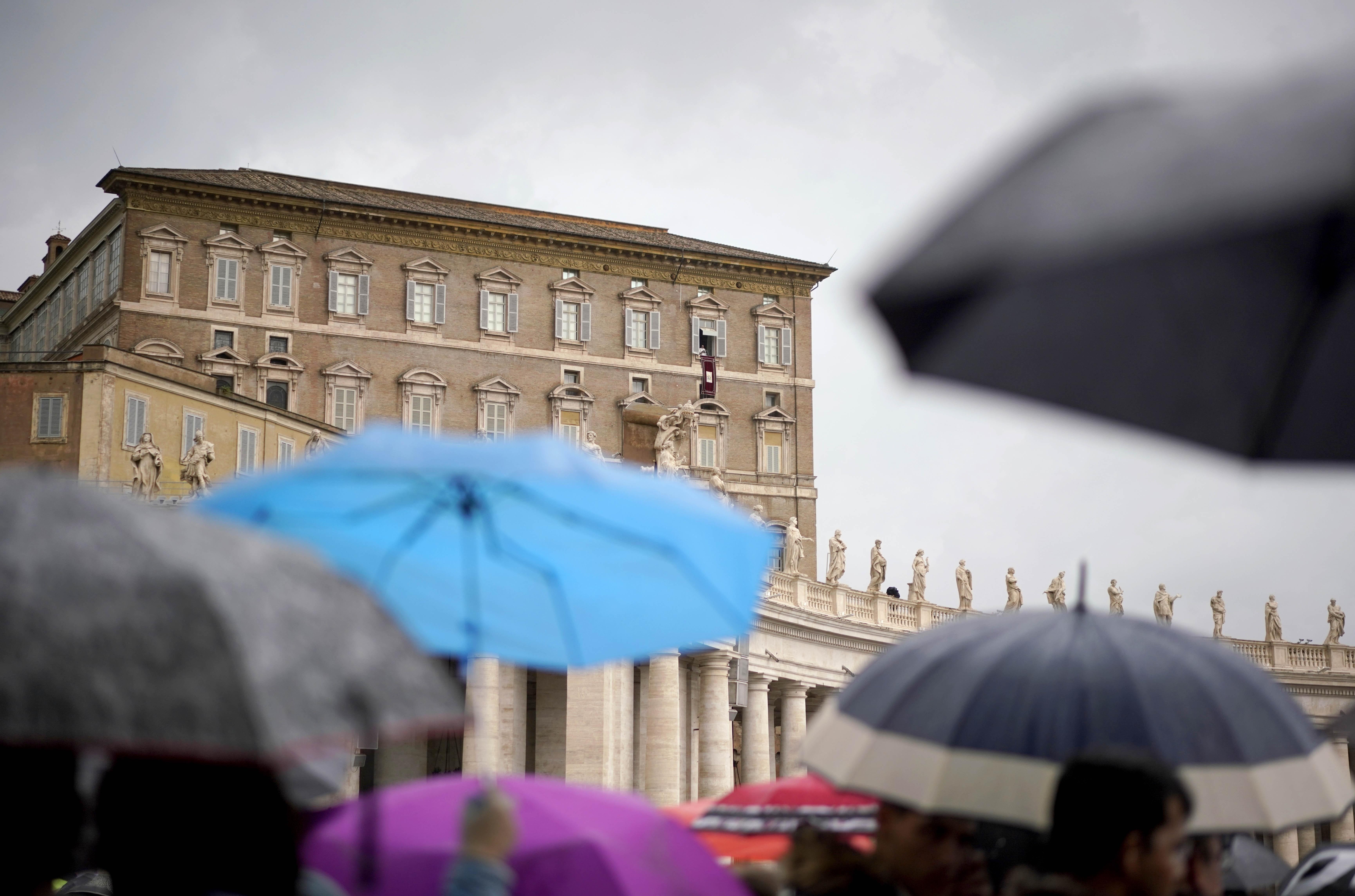 People shelter themselves from the rain as Pope Francis delivers his blessing from his studio window overlooking St. Peter's Square, at the Vatican, Sunday, Oct. 28, 2018. Francis is grieving with Pittsburgh's Jewish community following the massacre at a synagogue, denouncing the "inhuman act of violence" and praying for an end to the "flames of hatred" that fueled it. (AP Photo/Andrew Medichini)
            