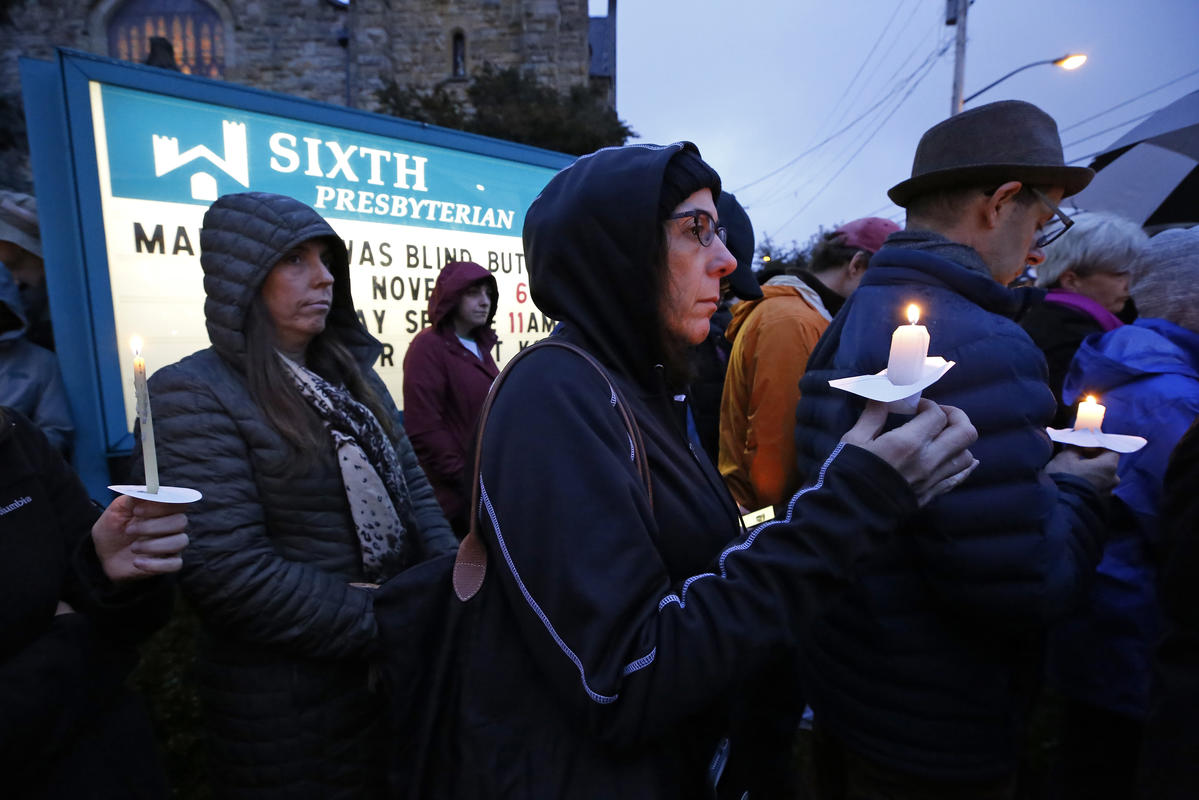 A crowd holds candles on the lawn of the Sixth Presbyterian Church at the intersection of Murray Ave. and Forbes Ave. in the Squirrel Hill section of Pittsburgh during a memorial vigil for the victims of the shooting at the Tree of Life Synagogue where a shooter opened fire earlier in the day, Saturday, Oct. 27, 2018. (AP Photo/Gene J. Puskar)
            