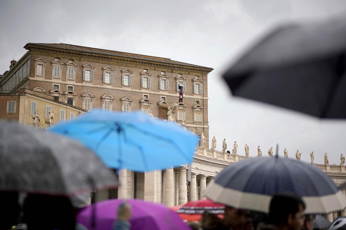 People shelter themselves from the rain as Pope Francis delivers his blessing from his studio window overlooking St. Peter's Square, at the Vatican, Sunday, Oct. 28, 2018. Francis is grieving with Pittsburgh's Jewish community following the massacre at a synagogue, denouncing the "inhuman act of violence" and praying for an end to the "flames of hatred" that fueled it. (AP Photo/Andrew Medichini)
            