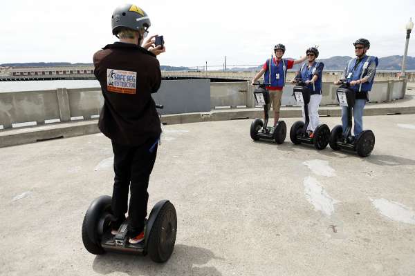 AG Palmer (left) takes of a photo of John Fourkas of Bethesda, Maryland (right) his wife Amy and son Austen during a Segway tour on Municipal Pier in San Francisco, Calif. on Tuesday, August 12, 2014.