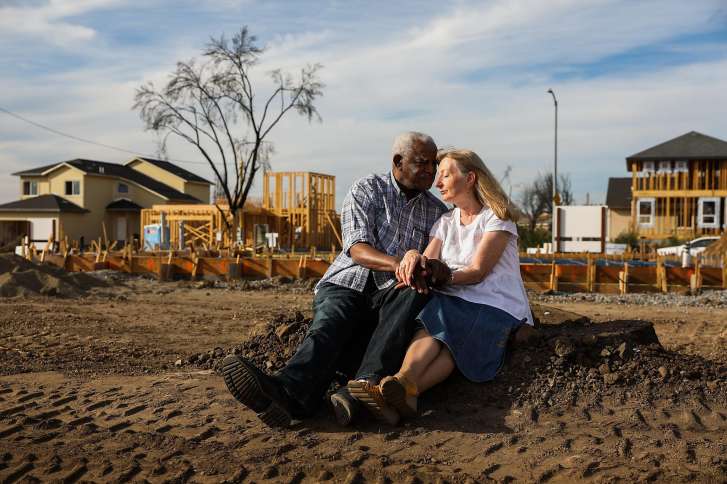 Husband and wife Henry Granger and Astrid Granger sit for a portrait on the stump of the Redwood tree that used to be part of their backyard before the Tubbs Fire destroyed their home in Santa Rosa, California, on Thursday, Sept. 27, 2018.