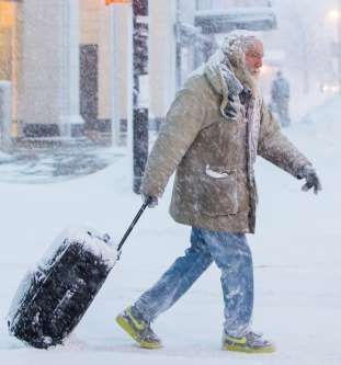 A man walks with luggage during a winter storm in Buffalo, New York, on Wednesda...