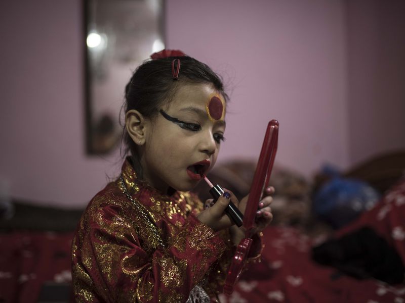 The Living Goddess of Nepal applies some makeup in her home inside the Kumari Temple of Patan in Kathmandu Valley. The usual Goddess make up is a black eyeliner and a big red "tikka" on the forehead that is believed to awaken the 3rd eye and to give power. 