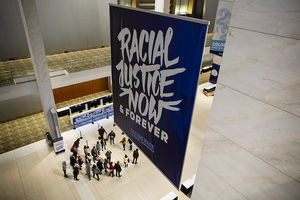 A convention hall with a large navy blue banner that says "Racial Justice Now & Forever"