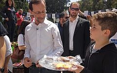 Sixth grade students in Tel Aviv holding a bake sale to raise money for their end of year party show off their baked goods to Zehut party candidate Moshe Feiglin outside a voting booth on April 9, 2019. Feiglin did not support the bake sale. (Melanie Lidman/Times of Israel)